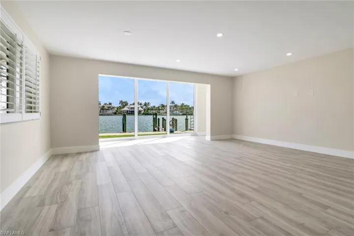 Empty room featuring light wood-type flooring, a water view, and recessed lighting