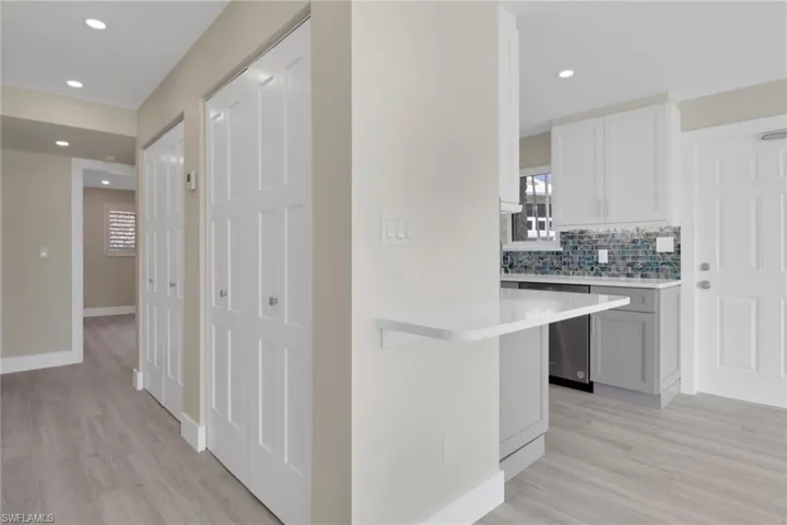 Kitchen with light wood finished floors, backsplash, recessed lighting, dishwasher, and white cabinets