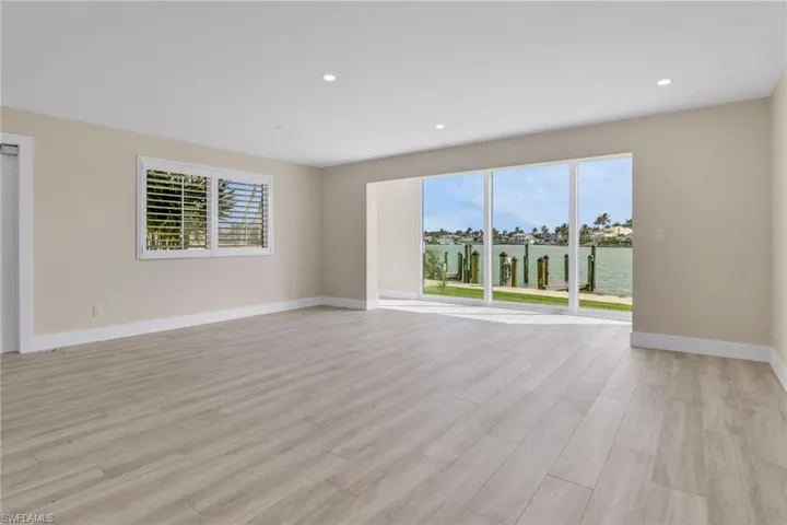 Empty room with a water view, light wood-style floors, and recessed lighting