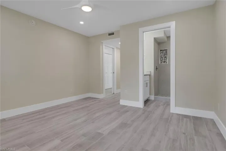 Unfurnished bedroom with light wood-type flooring, a ceiling fan, ensuite bathroom, and recessed lighting