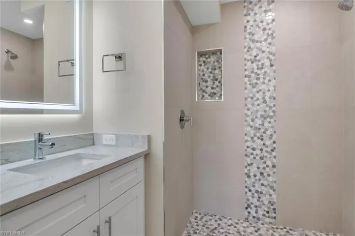 Bathroom featuring a tile shower and vanity