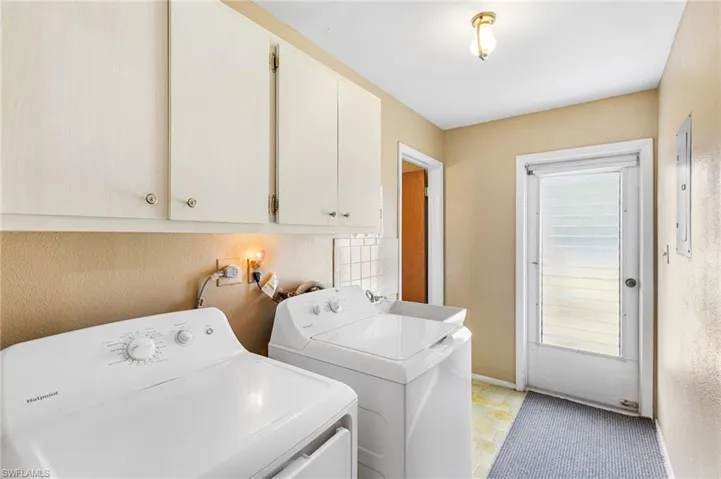 Washroom with cabinets, washer and dryer, electric panel, and a healthy amount of sunlight