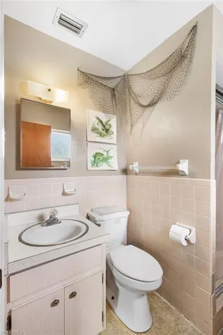Bathroom featuring tile walls, toilet, and vanity