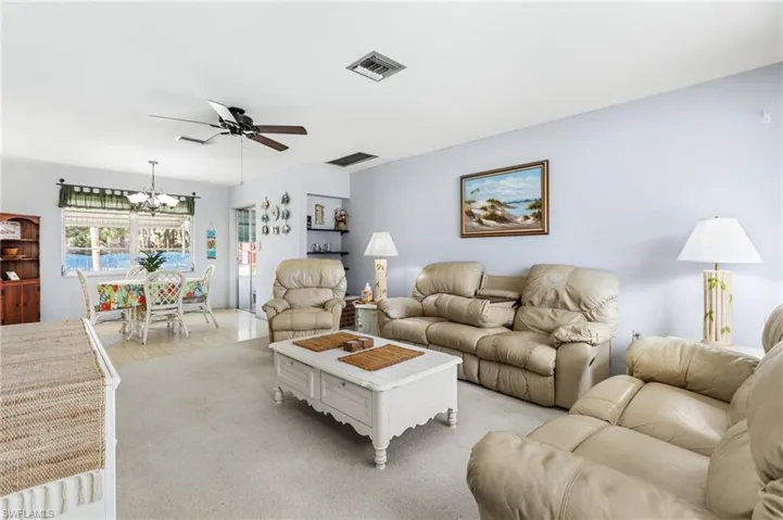 Carpeted living room with ceiling fan with notable chandelier