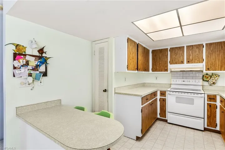 Kitchen featuring tasteful backsplash, kitchen peninsula, and white electric range