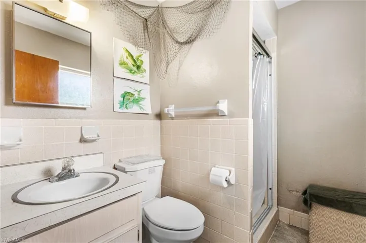 Bathroom featuring tile walls, vanity, a shower with shower curtain, and toilet