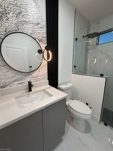 Full bathroom with vanity, a marble finish shower, and light marble finish flooring