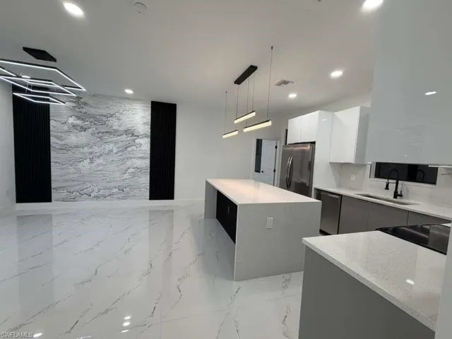Kitchen with modern cabinets, light marble finish floors, light stone counters, appliances with stainless steel finishes, and recessed lighting