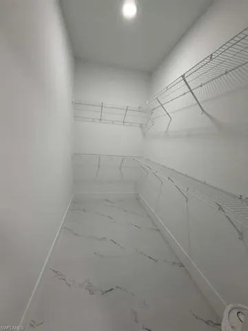Spacious closet featuring light marble finish flooring