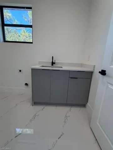 Laundry area featuring light marble finish floors, cabinet space, and hookup for an electric dryer