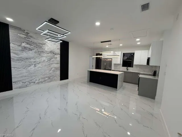 Kitchen with modern cabinets, a center island, decorative light fixtures, freestanding refrigerator, and recessed lighting