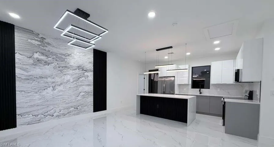 Kitchen featuring modern cabinets, a center island, hanging light fixtures, electric stove, and freestanding refrigerator