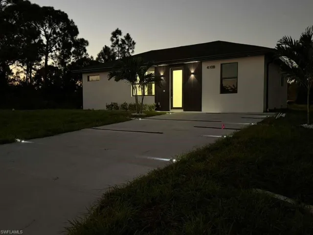 View of front facade with a front lawn, concrete driveway, a patio, and stucco siding