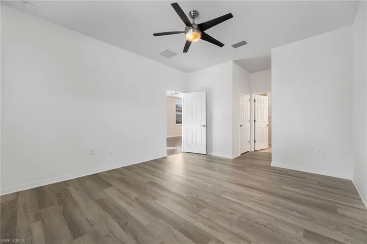 Unfurnished room featuring wood finished floors, visible vents, and baseboards