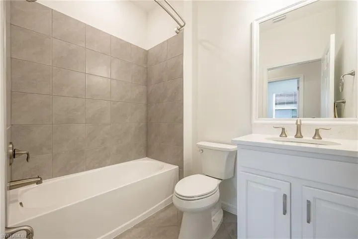 Bathroom featuring toilet, vanity, tub / shower combination, and tile patterned floors