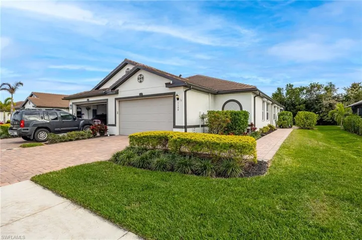 View of front facade featuring decorative driveway, stucco siding, an attached garage, a front yard, and a tiled roof