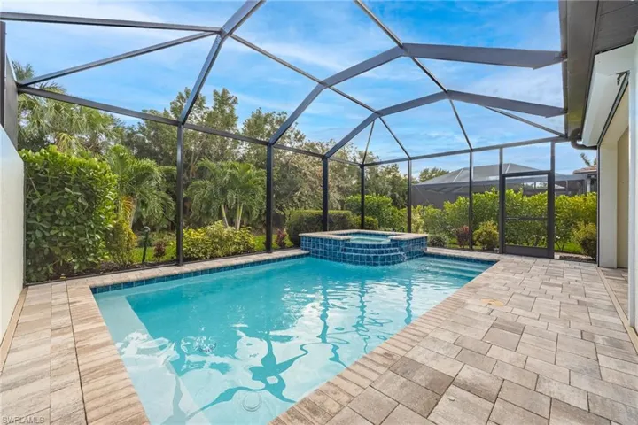 View of pool featuring a patio area, a pool with connected hot tub, and glass enclosure