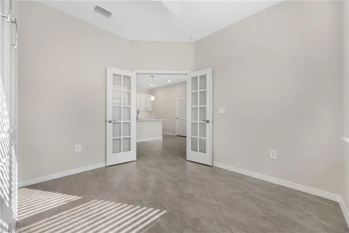 Spare room featuring light tile patterned floors, baseboards, visible vents, and french doors