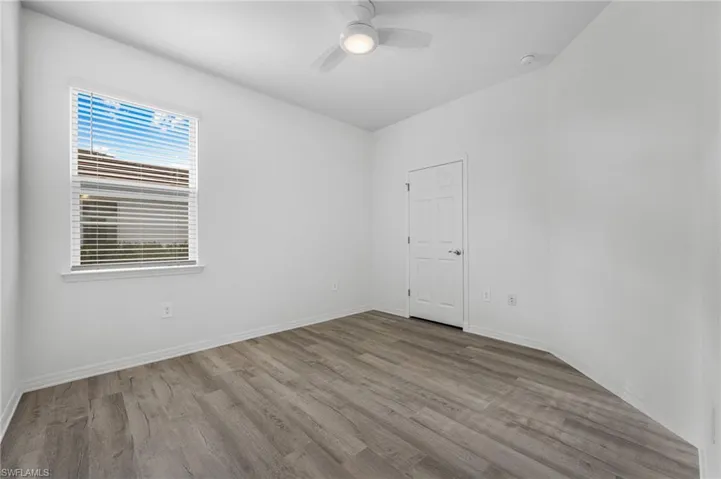 Unfurnished room with ceiling fan, light wood-style flooring, and baseboards