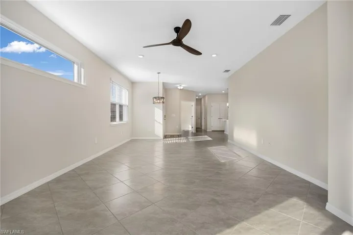 Unfurnished living room featuring ceiling fan, visible vents, and baseboards