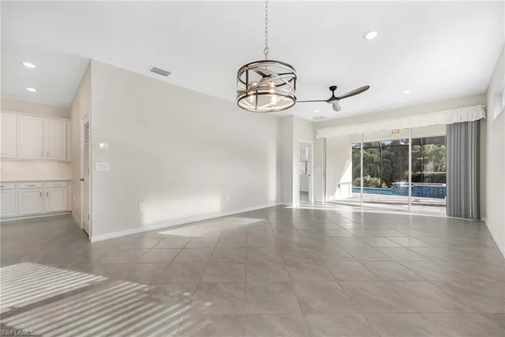 Unfurnished room featuring ceiling fan with notable chandelier, light tile patterned floors, recessed lighting, and baseboards