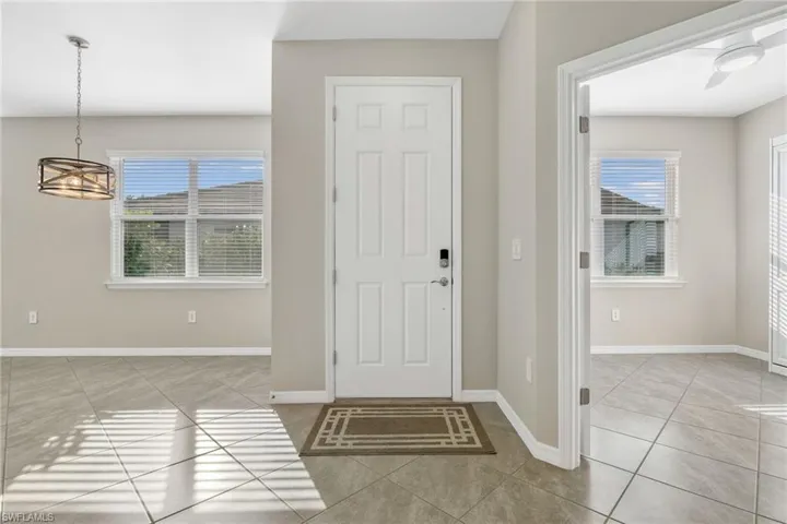Foyer with a ceiling fan, baseboards, and light tile patterned floors
