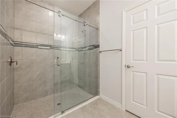 Full bath with tile patterned flooring, a shower stall, and baseboards