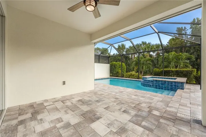 View of swimming pool with glass enclosure, a patio area, and a pool with connected hot tub