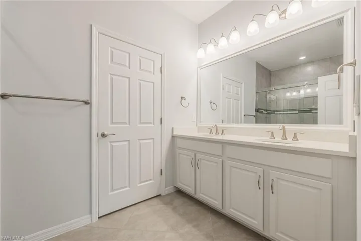 Full bath with a stall shower, tile patterned flooring, a sink, and baseboards