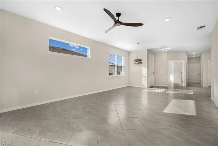 Empty room featuring ceiling fan, light tile patterned floors, recessed lighting, visible vents, and baseboards