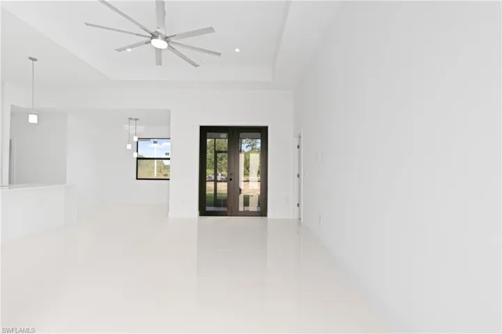 Unfurnished room featuring a raised ceiling, french doors, light tile patterned floors, recessed lighting, and a ceiling fan
