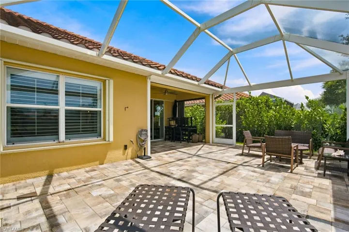 Screened outdoor patio featuring paver flooring, stucco exterior, and a tile roof