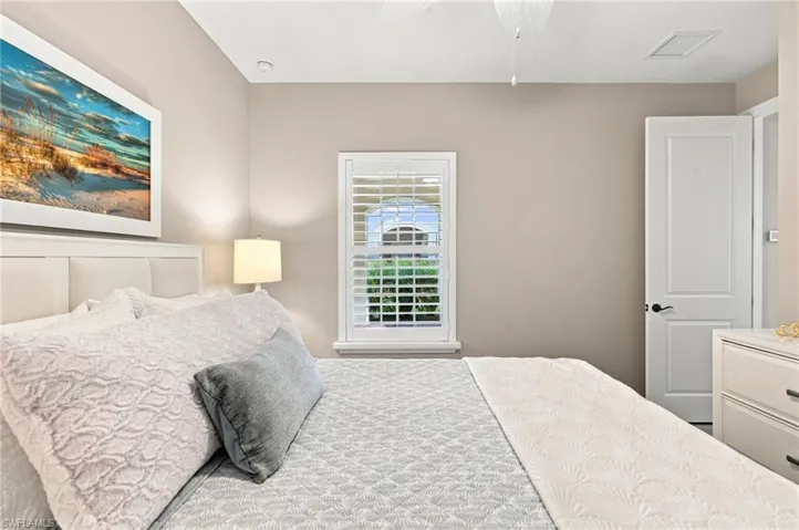 White paneled headboard with an upholstered back, featuring a window with white plantation shutters