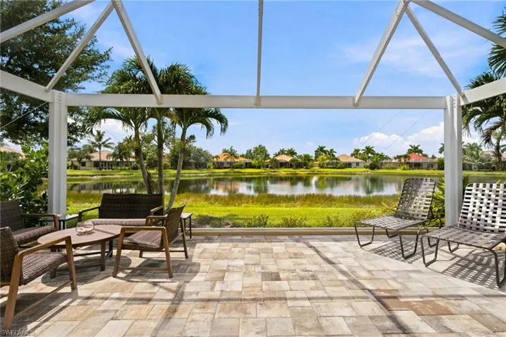 Expansive outdoor patio featuring a screened enclosure, paver flooring, and direct water frontage