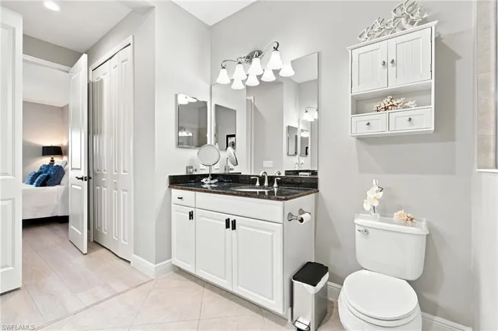 Bathroom featuring a single vanity with dark countertop, white cabinetry, and brushed nickel hardware
