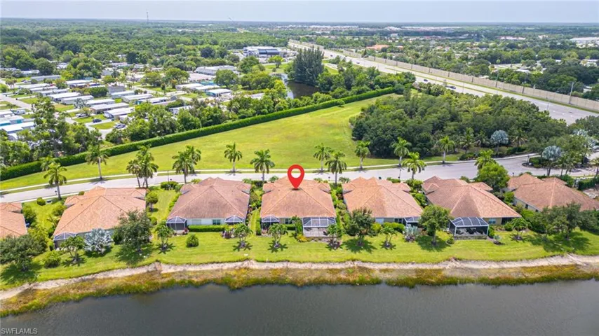 Waterfront residential property featuring a shingle roof and a screened-in rear patio