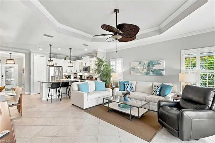 Open-concept living space featuring a tray ceiling, tile flooring, and white plantation shutters
