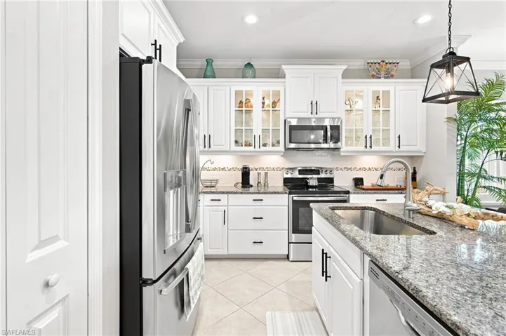 Kitchen featuring white shaker cabinetry, stainless steel appliances, granite countertops, and tile flooring