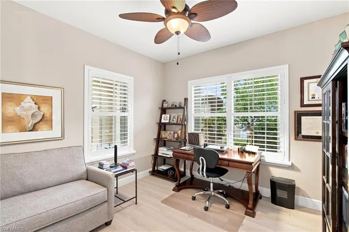 Room featuring light-toned walls, wood-finish flooring, and white plantation shutters on multiple windows