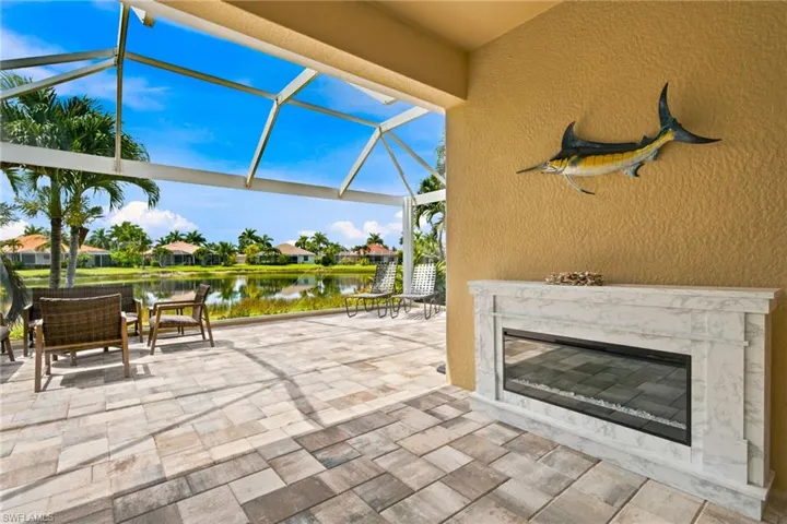 Screened patio with paver flooring, featuring a built-in fireplace with a stone-finish surround
