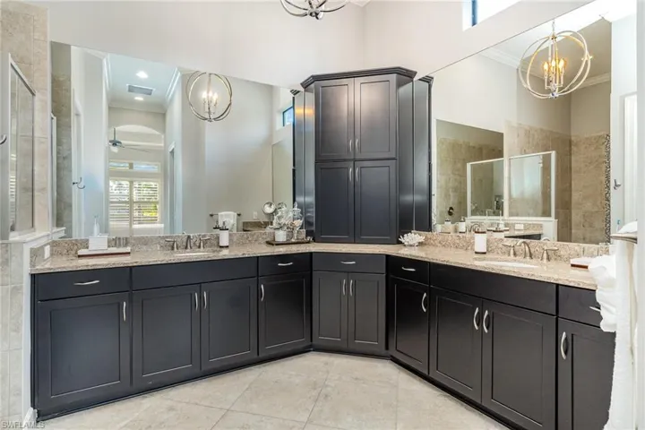 Bathroom featuring ceiling fan with notable chandelier, an enclosed shower, crown molding, and vanity