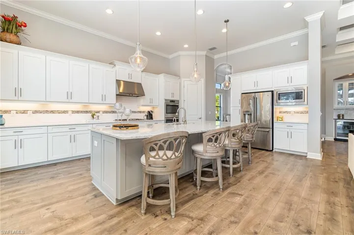 Kitchen with white cabinets, appliances with stainless steel finishes, a healthy amount of sunlight, and an island with sink