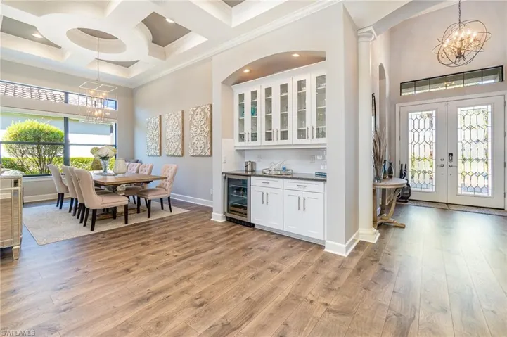 Kitchen with white cabinets, light hardwood / wood-style flooring, decorative backsplash, decorative light fixtures, and beverage cooler