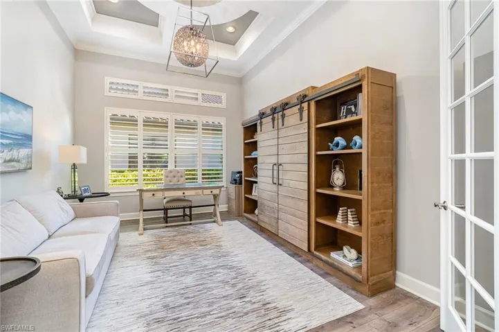 Office area featuring hardwood / wood-style floors, a barn door, crown molding, and a high ceiling