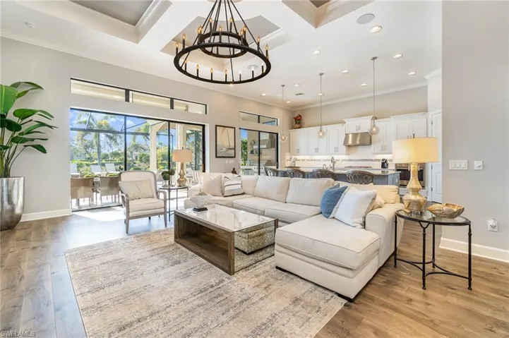 Living room featuring coffered ceiling, a chandelier, ornamental molding, and light hardwood / wood-style flooring