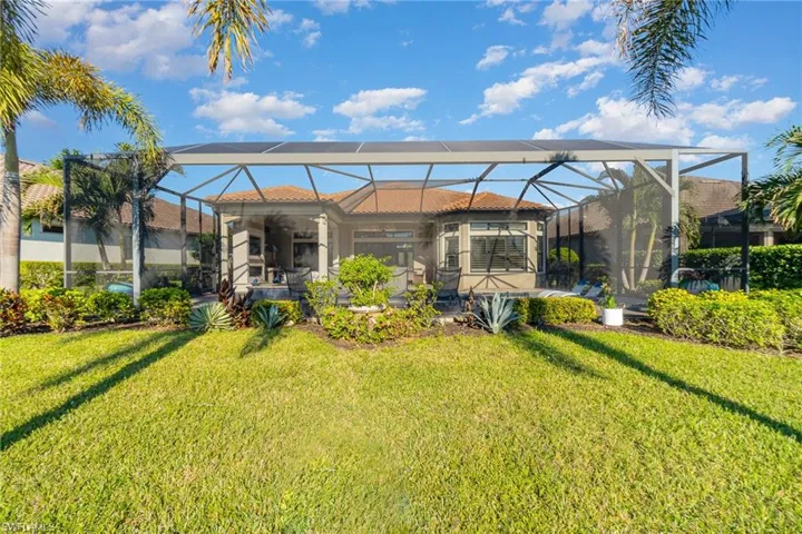 Back of property with a lanai and a lawn