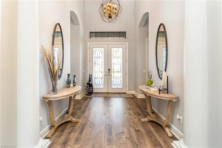 Entryway featuring french doors, dark wood-type flooring, and a notable chandelier