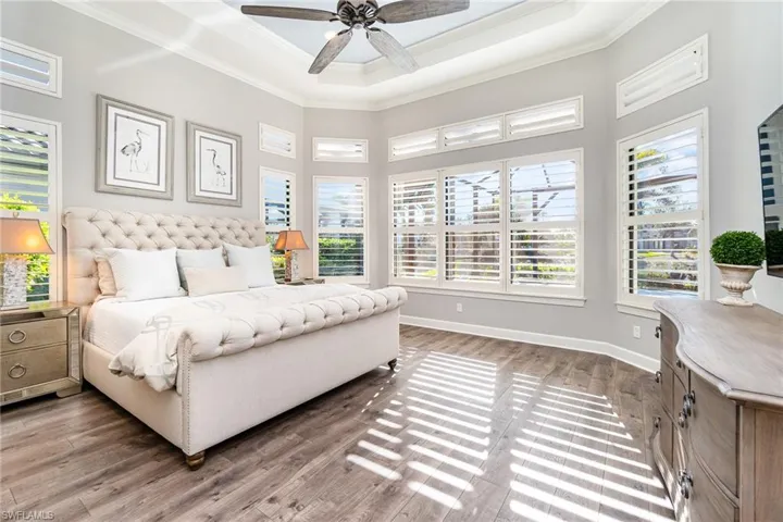 Bedroom featuring ceiling fan, dark hardwood / wood-style flooring, crown molding, and a tray ceiling