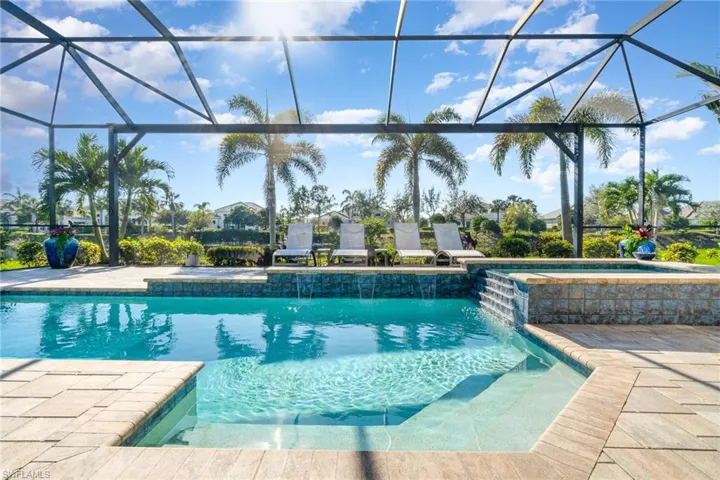 View of swimming pool with pool water feature, a patio area, a lanai, and an in ground hot tub