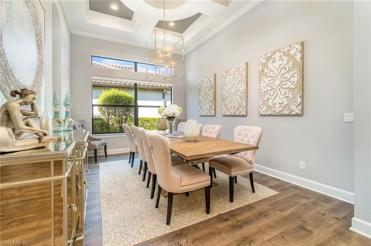 Dining area featuring dark wood-type flooring, a high ceiling, coffered ceiling, crown molding, and beamed ceiling